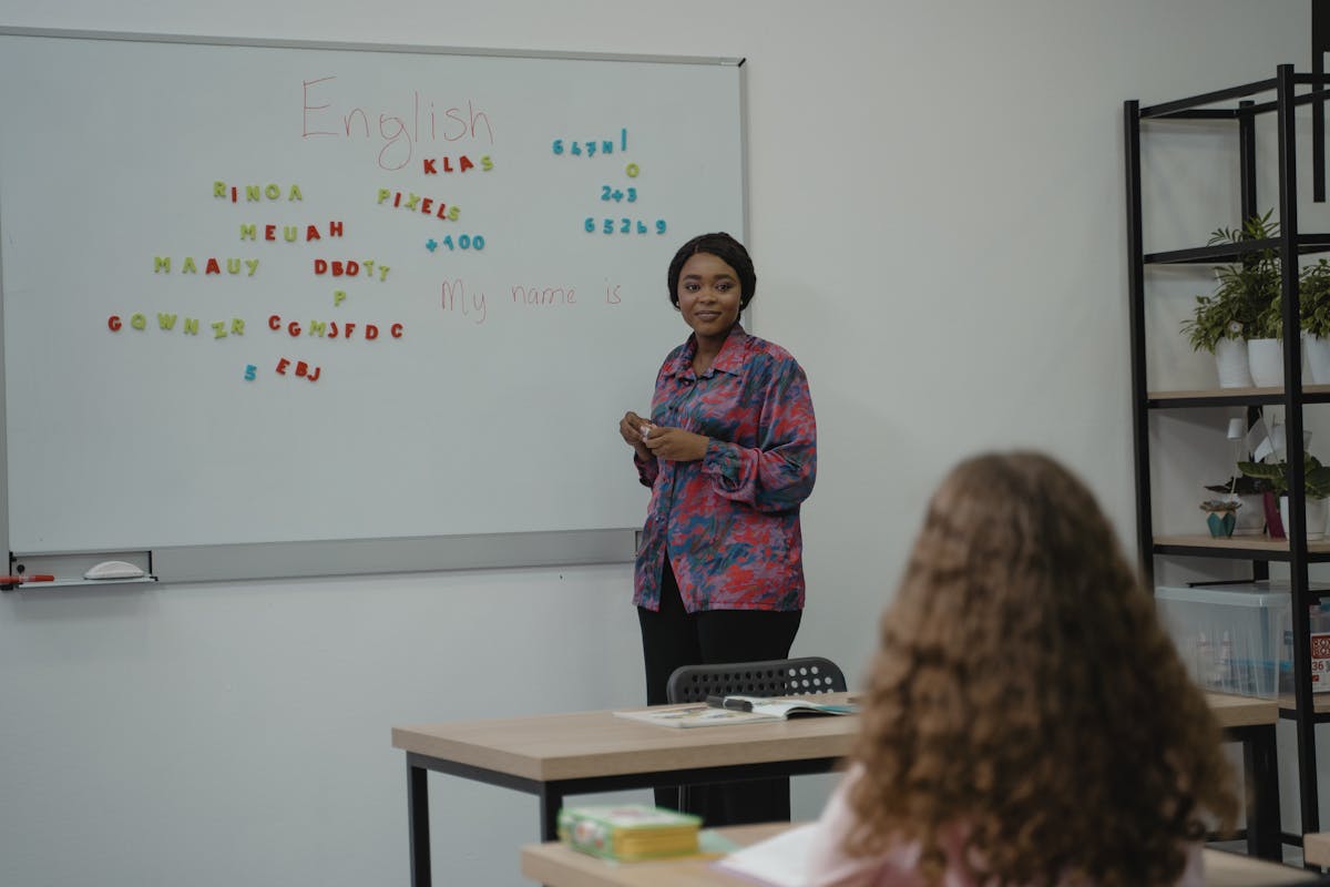 ESL teacher explaining English language concepts on a whiteboard to a student