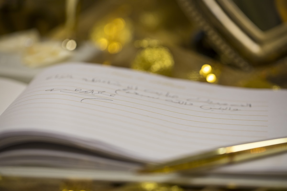 A golden pen resting on a notebook ready for creative ESL writing practice