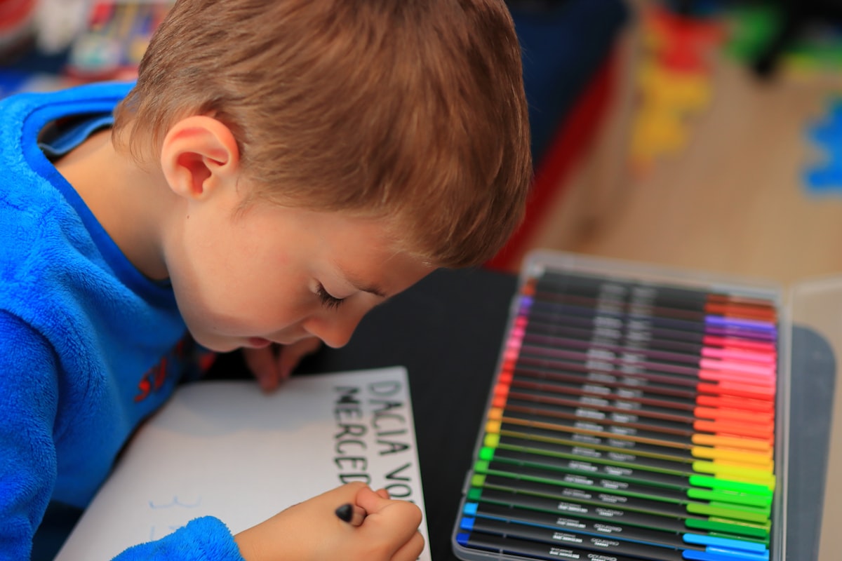 Young student writing with colored pencils during an ESL writing activity at school