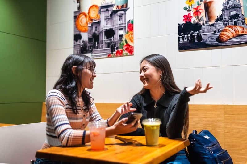 Two adults practicing English conversation at a cafe