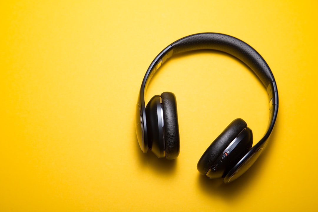 Pretty lady in headphones is listening to music in modern apartment enjoying favorite song typing on laptop. People, relaxati