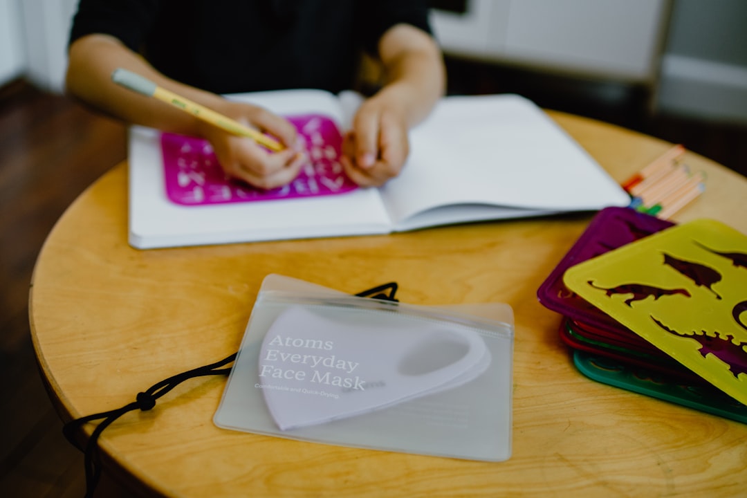 Girl drawing in notebook with mask nearby