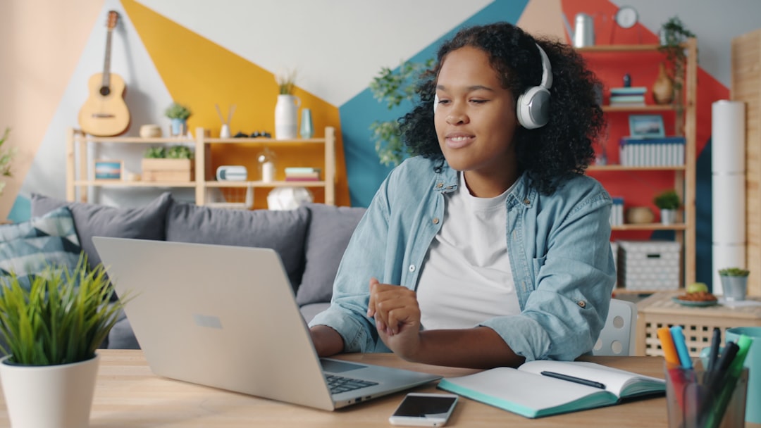 Pretty lady in headphones is listening to music in modern apartment enjoying favorite song typing on laptop. People, relaxati