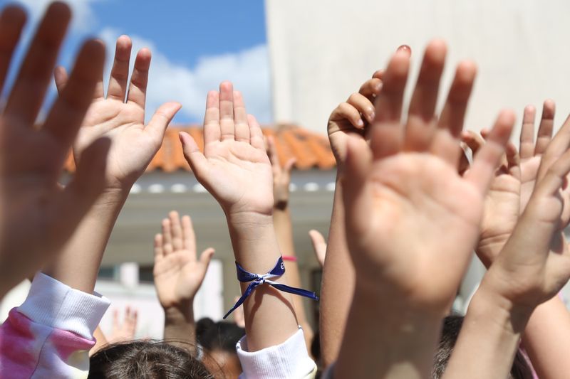 ESL students with hands raised showing strong engagement during a lesson