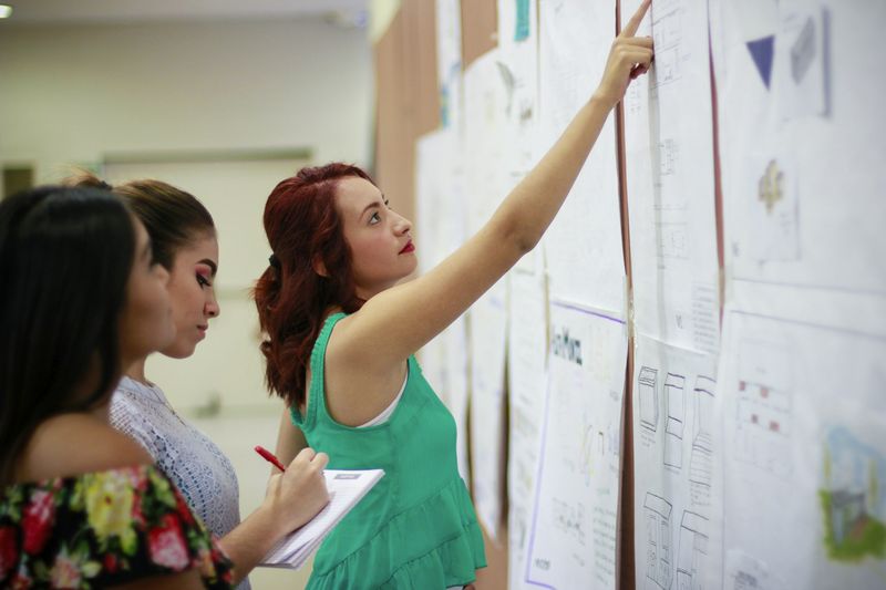 ESL lesson plan review and reflection — teachers analyzing materials on a wall