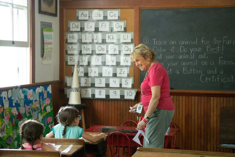 Teacher leading ESL pronunciation activities in a classroom with alphabet wall