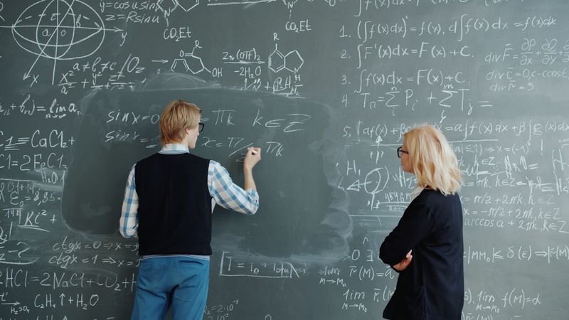 ESL teacher helping student at chalkboard