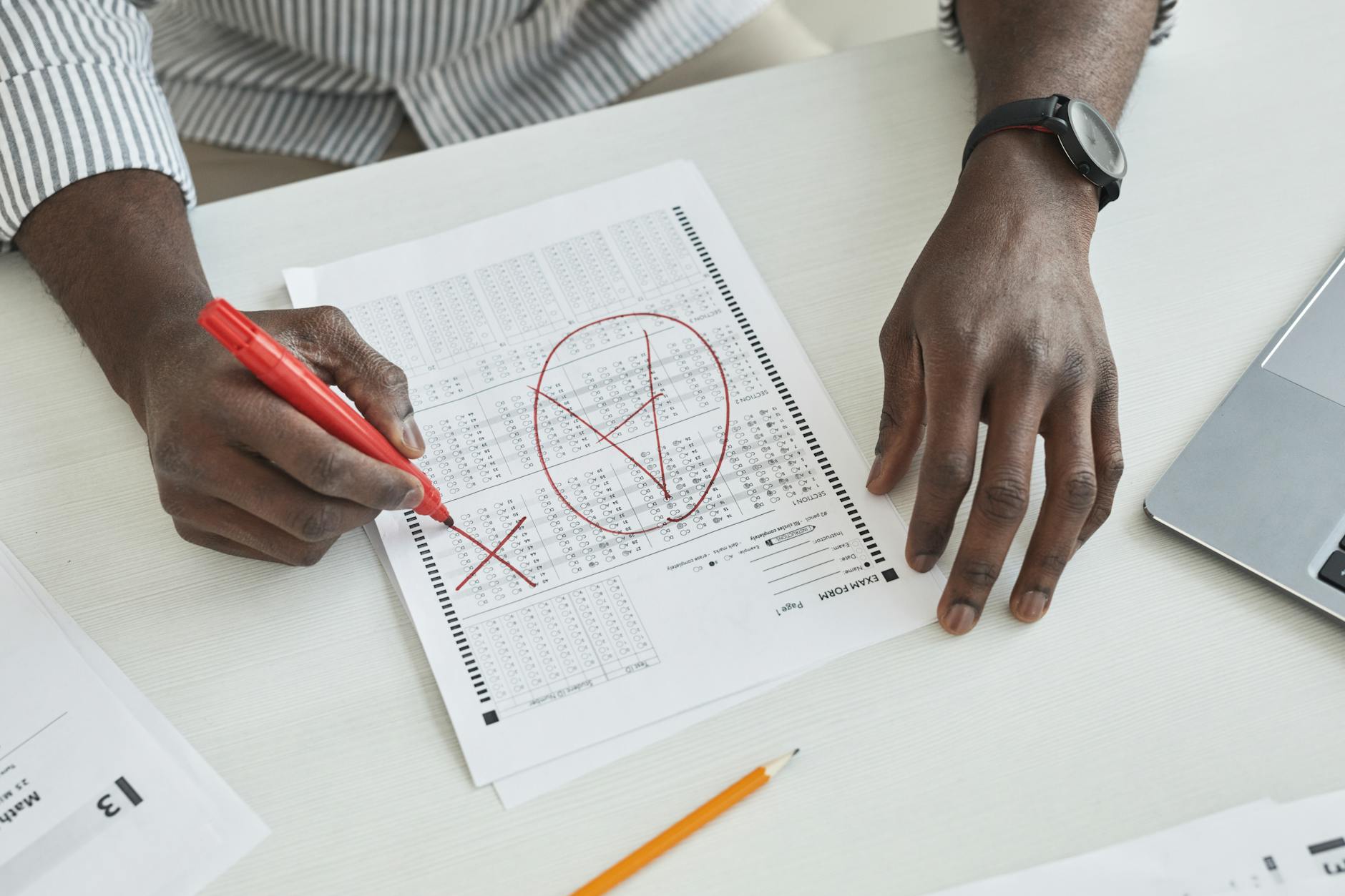 ESL teacher reviewing student exam papers at a classroom desk