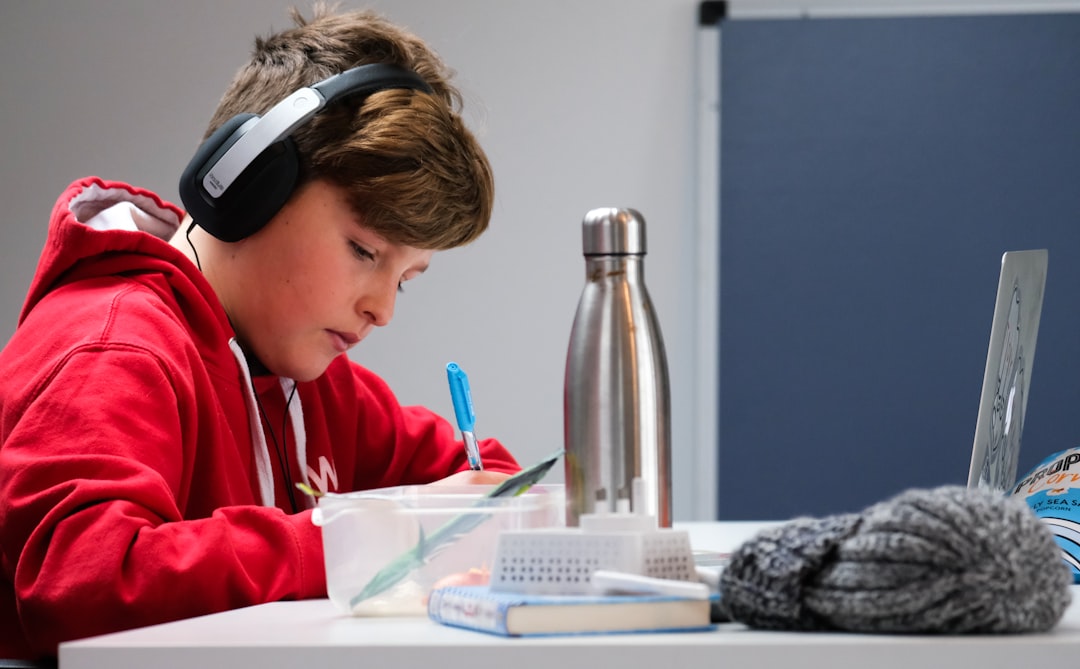 Home schooling during lockdown, boy working on school work with laptop and headphones during coronavirus covid 19 lock down.