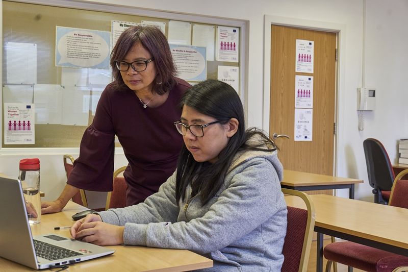 ESL teacher giving individual error correction feedback at a laptop