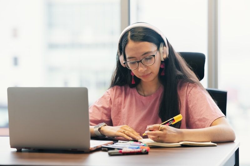 Student taking notes while watching a flipped classroom lesson on a laptop