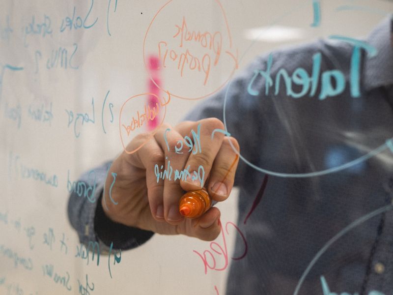 Teacher writing phrasal verbs lesson on a whiteboard
