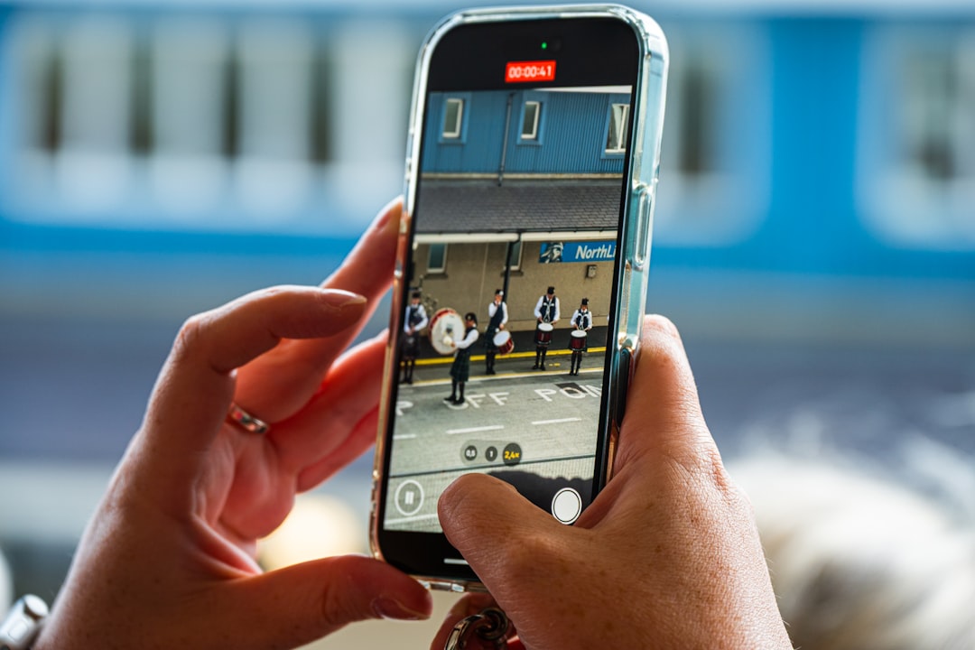 Hands holding a smartphone recording a subway platform.