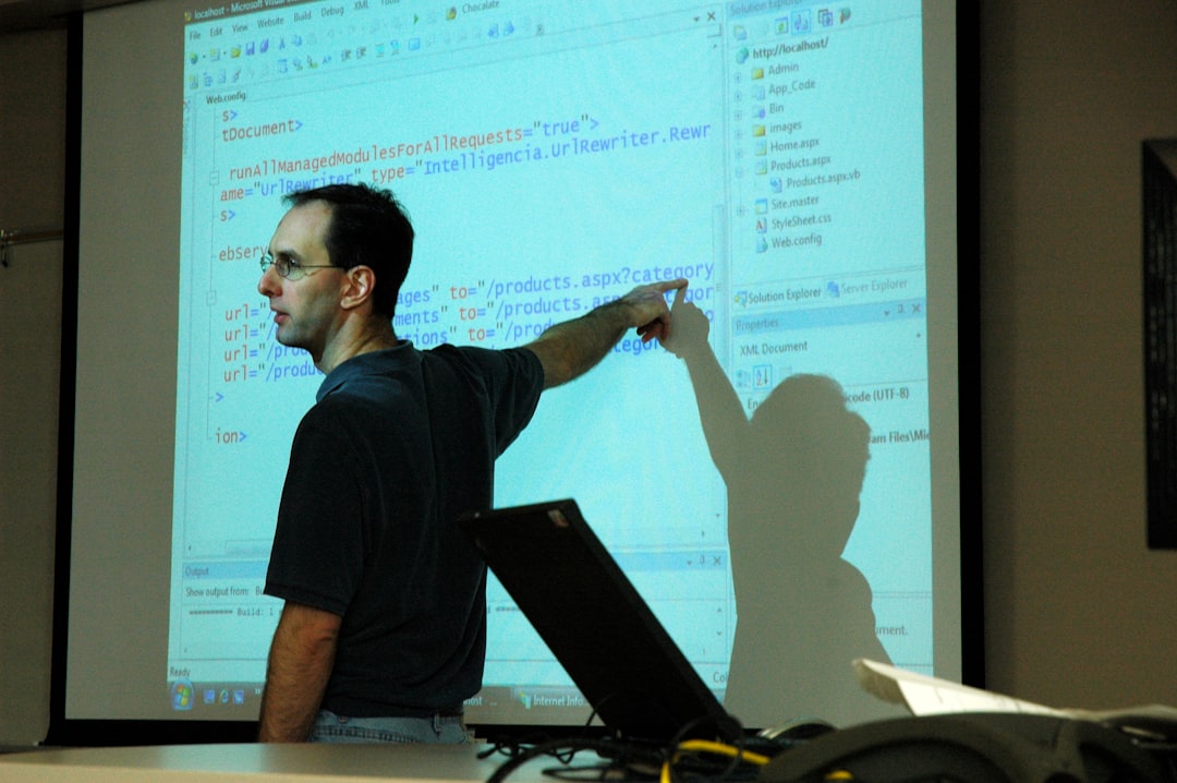 Computer science teacher, teaching coding or scripting, PowerPoint slide show, open laptop, papers, wires, Information school