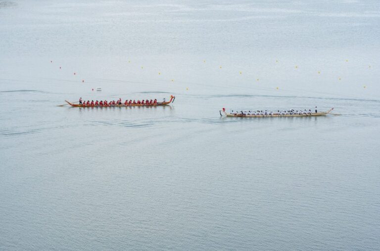 Aerial shot of two dragon boats racing on calm waters, showcasing teamwork and competition.