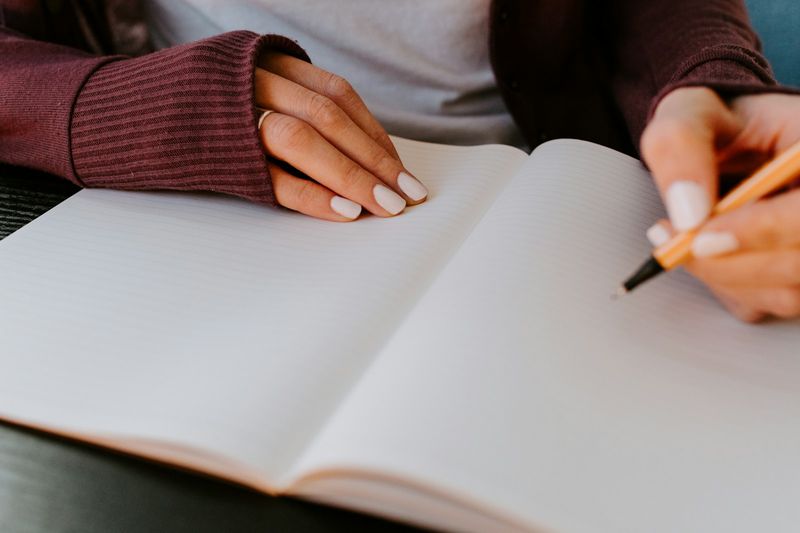 Hands ready to write in an open journal for a free writing ESL task