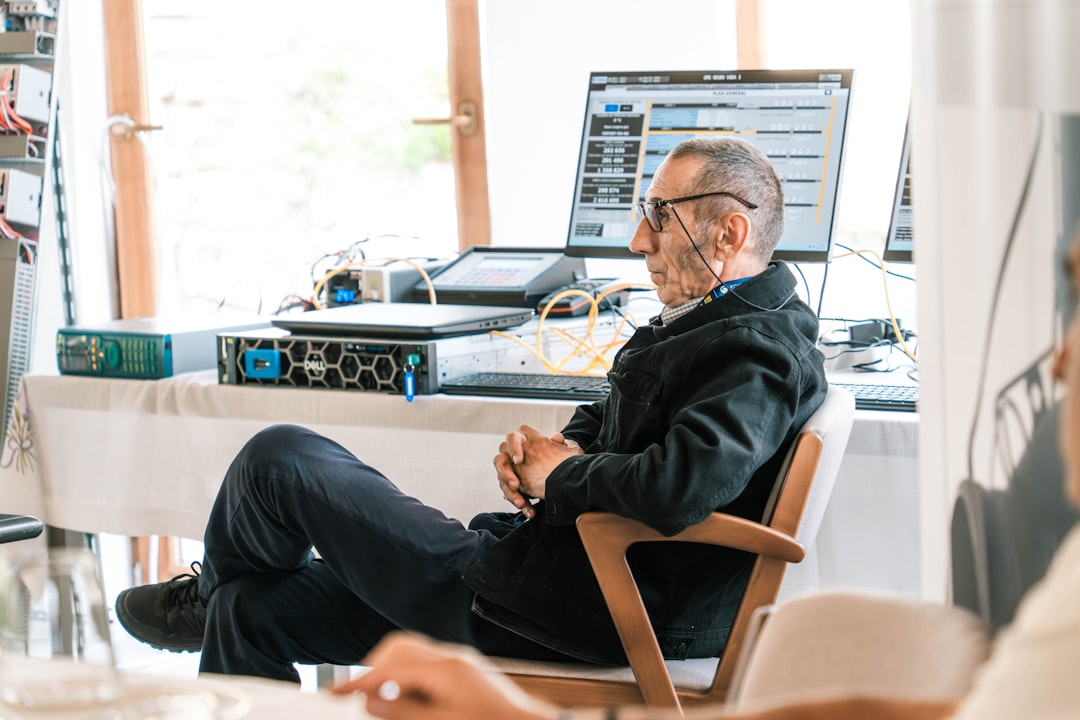 A man sitting at a desk with computer equipment.