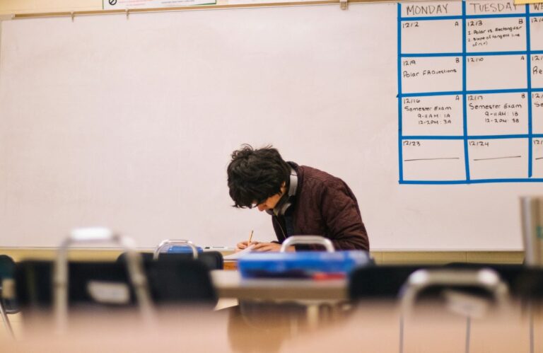 Teaching paragraph structure to a student writing at a classroom desk