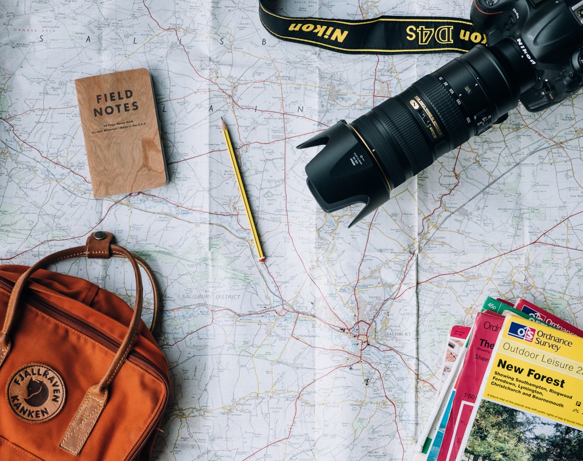 Flat-lay of a travel map, backpack, camera and guidebook laid out for trip planning Flat-lay of a travel map, backpack, camera and guidebook laid out for trip planning