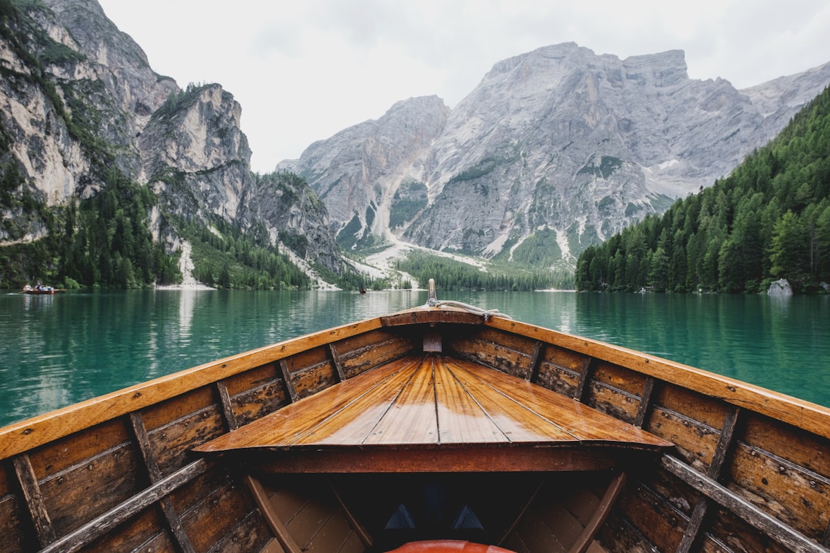 View from a wooden boat gliding across a turquoise alpine lake, off the beaten path View from a wooden boat gliding across a turquoise alpine lake, off the beaten path