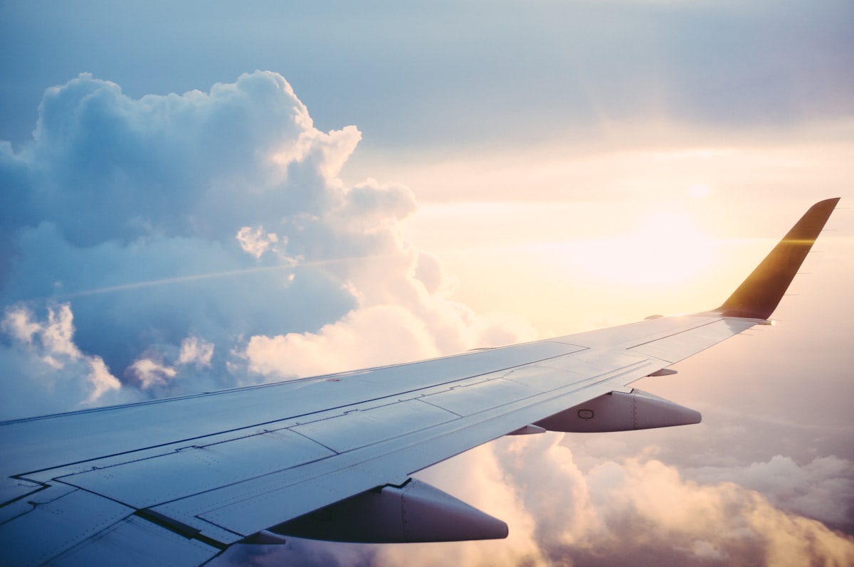 Airplane wing cutting through soft pink and blue clouds at sunset during a flight Airplane wing cutting through soft pink and blue clouds at sunset during a flight