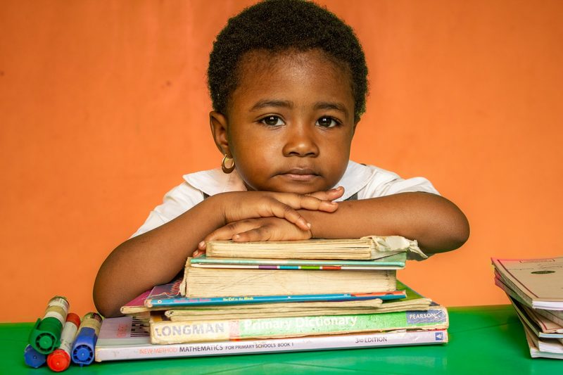 Young learner with a stack of books before a paragraph writing lesson