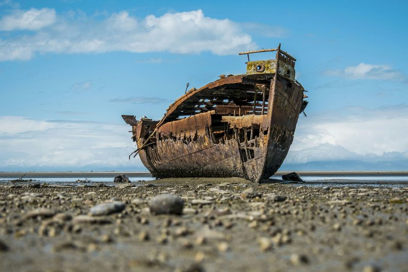 Rusted shipwreck on a barren shore standing in for Robinson Crusoe's wrecked vessel