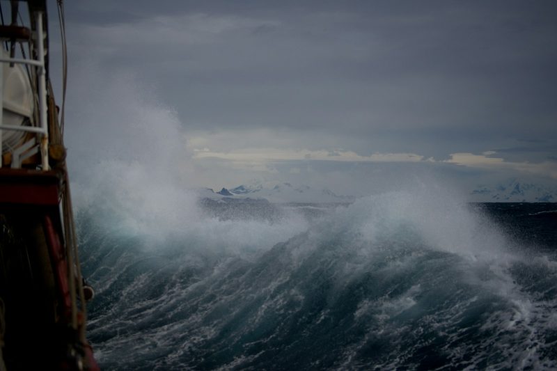 Stormy waves crashing over a ship's deck, echoing Robinson Crusoe's disastrous final voyage