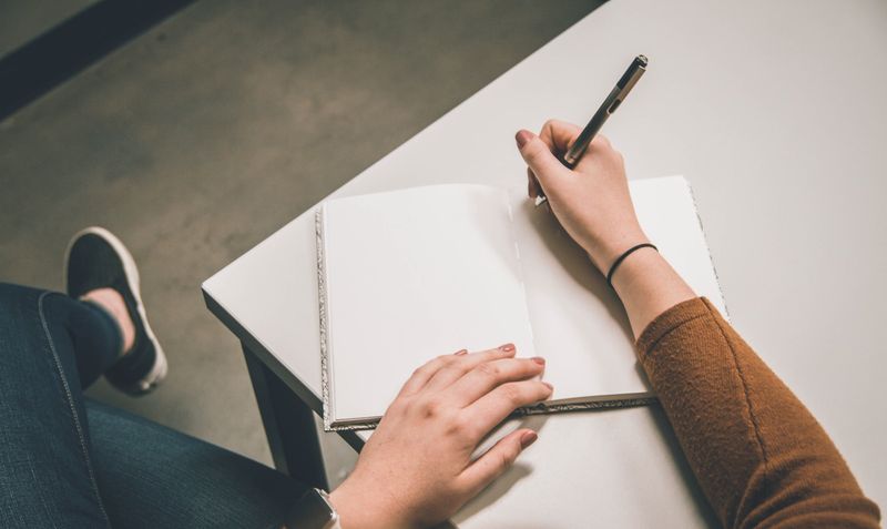 Student writing an essay for a writing competition in a notebook