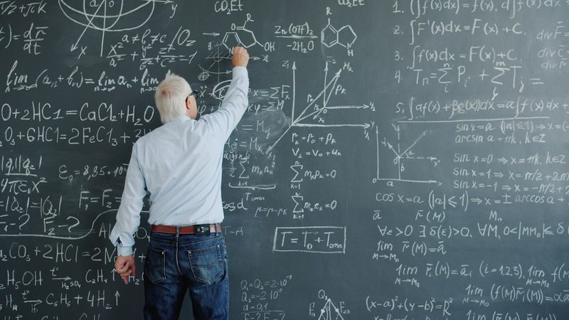 teacher writing quantifiers grammar rules on chalkboard