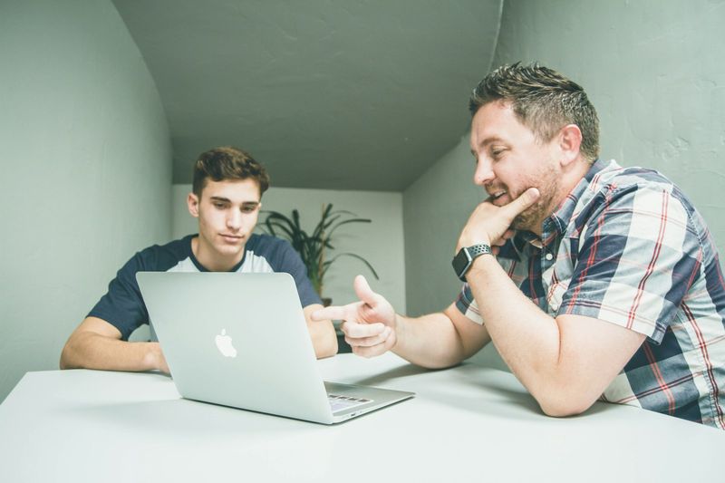 Teacher helping an adult beginner learn English on a laptop