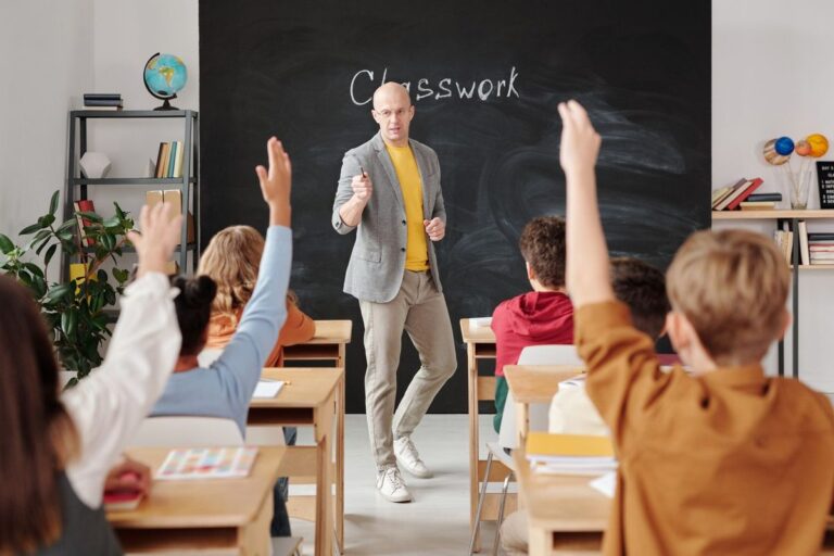 Teacher teaching comparatives and superlatives to ESL students raising their hands