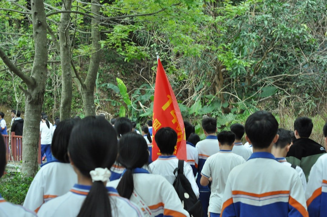 Students walk with a red flag in a park.