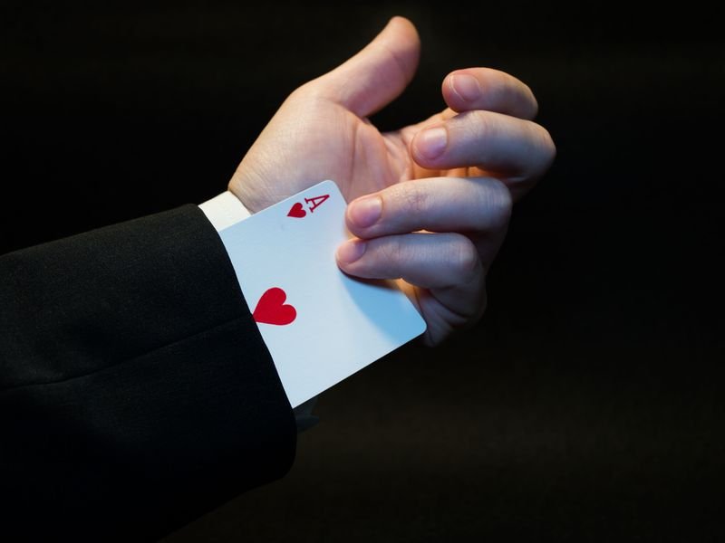 Magicians hand revealing a hidden ace of hearts up the sleeve illustrating ace up your sleeve idiom