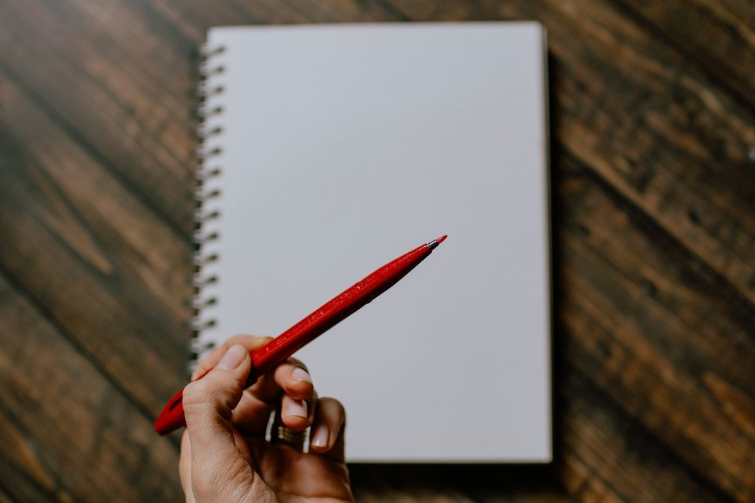 Red felt-tip pen over a blank notebook