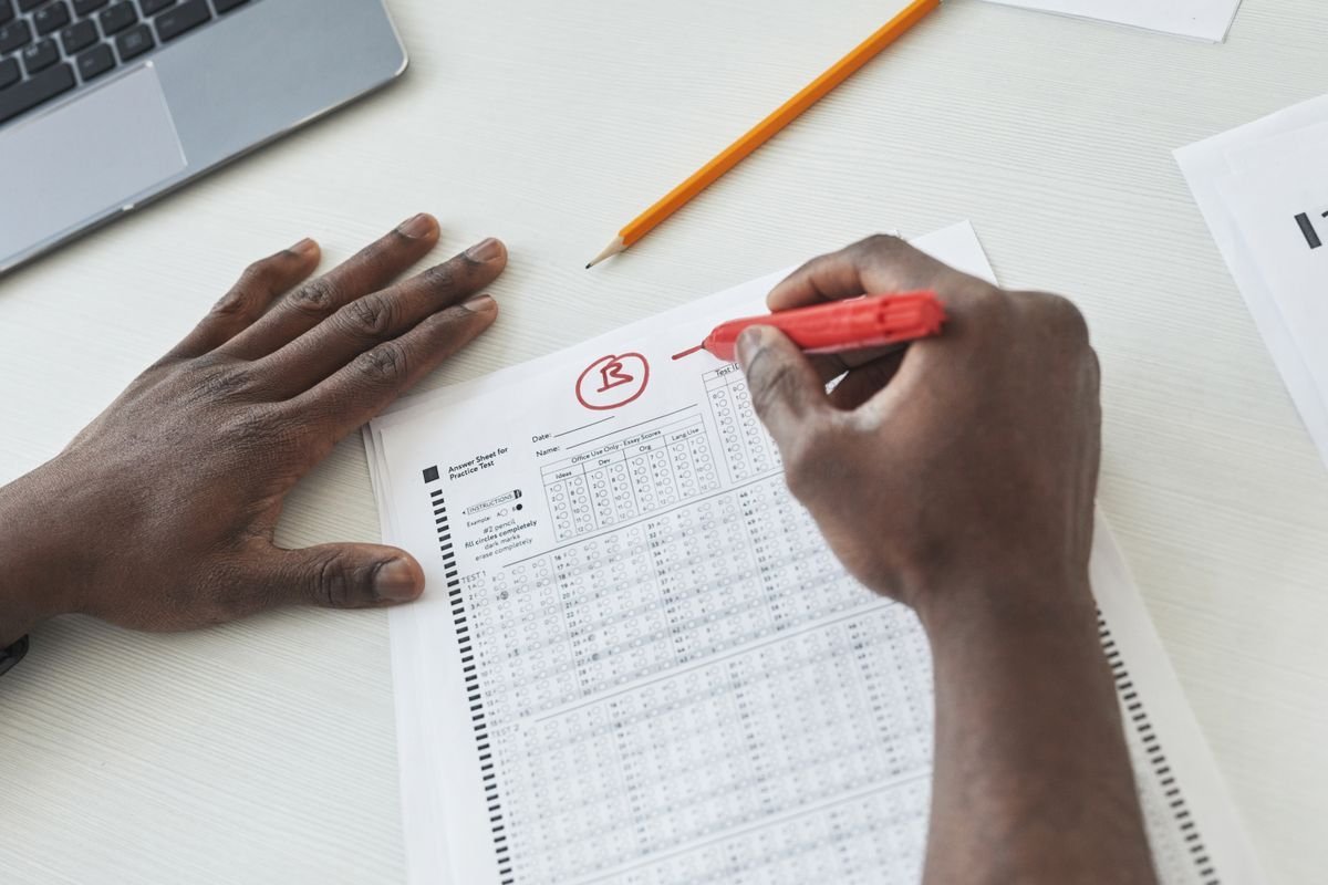 Teacher reviewing a student essay with a red pen at a desk