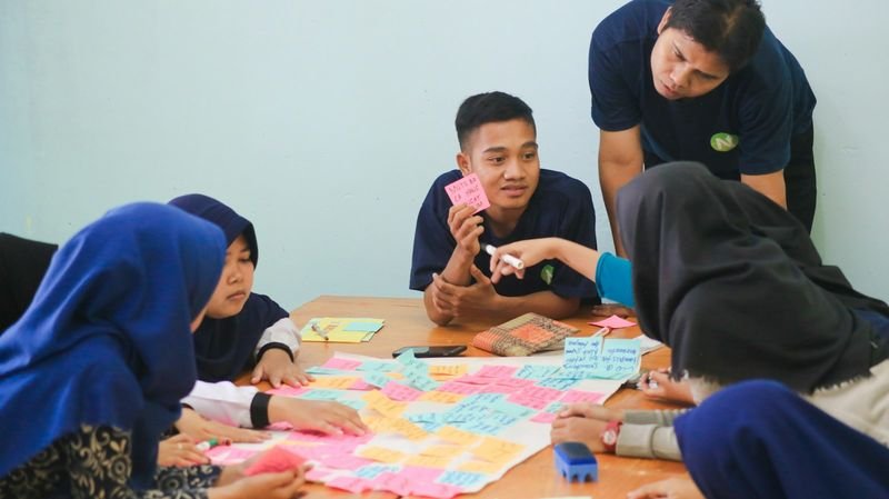 esl students huddled discussing grammar auction bidding strategy