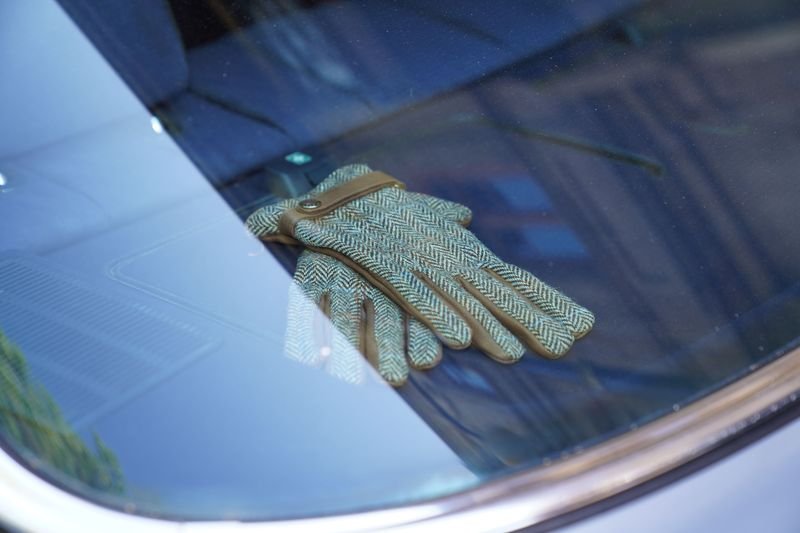 Classic leather gloves resting on a vintage dashboard illustrating handle with kid gloves idiom