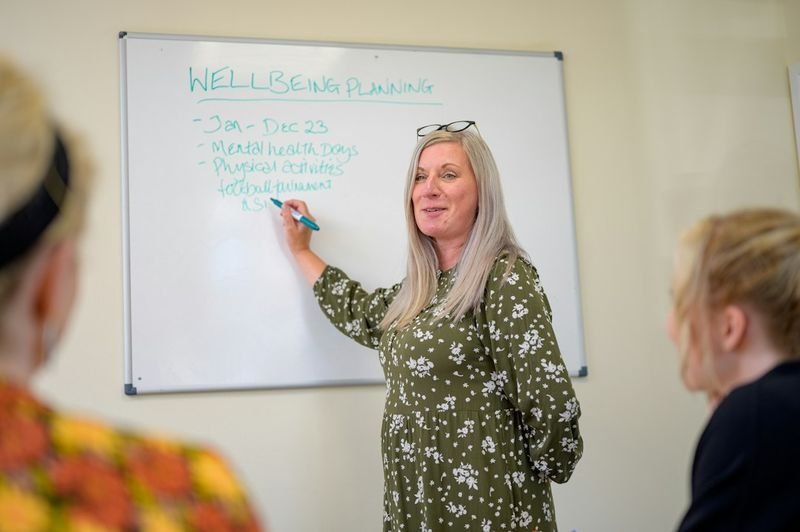 Teacher pointing at whiteboard explaining the order of adjectives rule to students