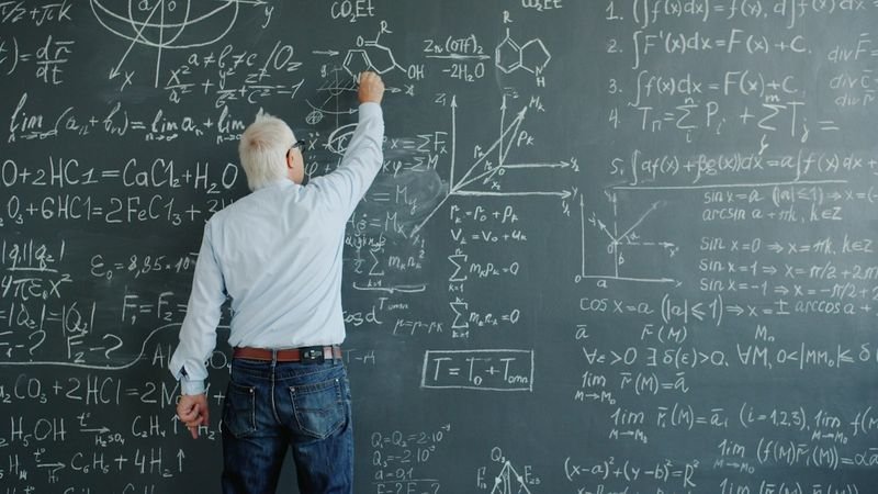 ESL teacher writing academic vocabulary on a blackboard during a content-based lesson