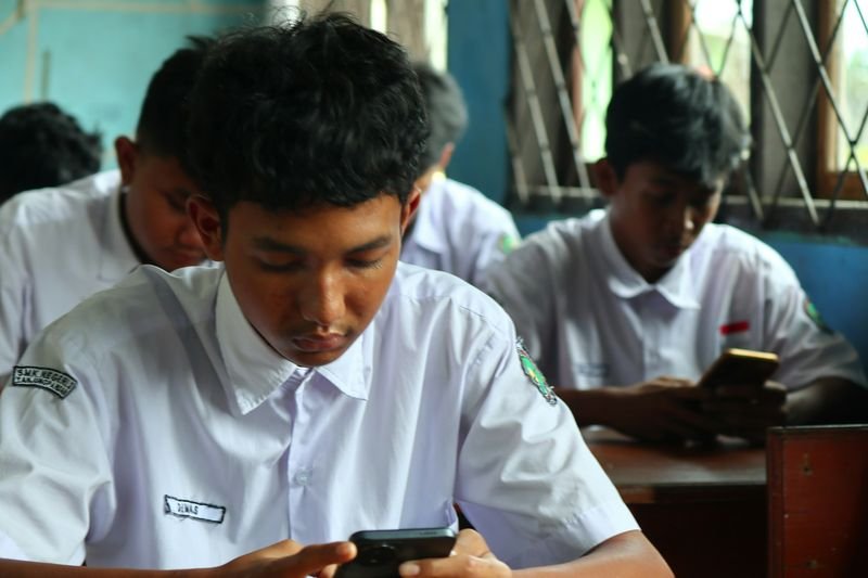 ESL students in uniform playing a live Kahoot quiz on their smartphones