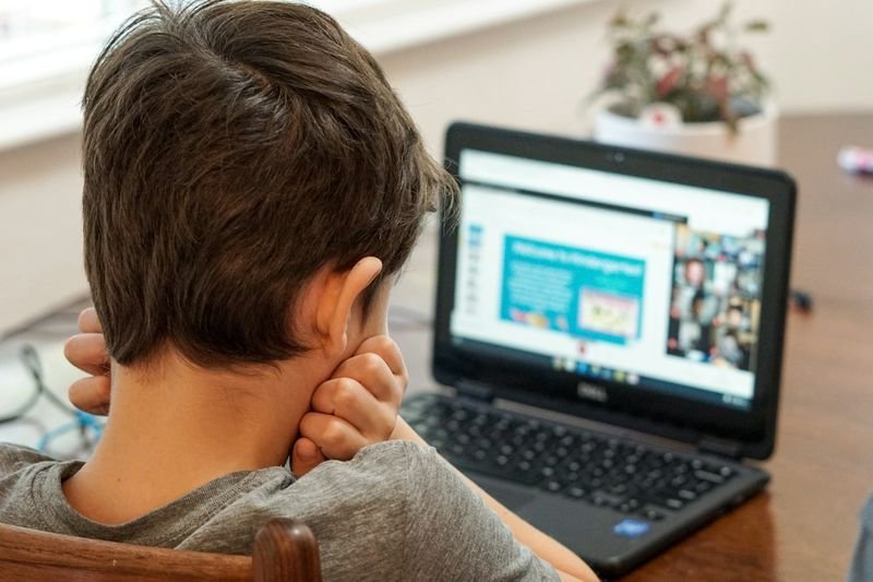 ESL student practicing an interactive LiveWorksheets exercise on a laptop at home