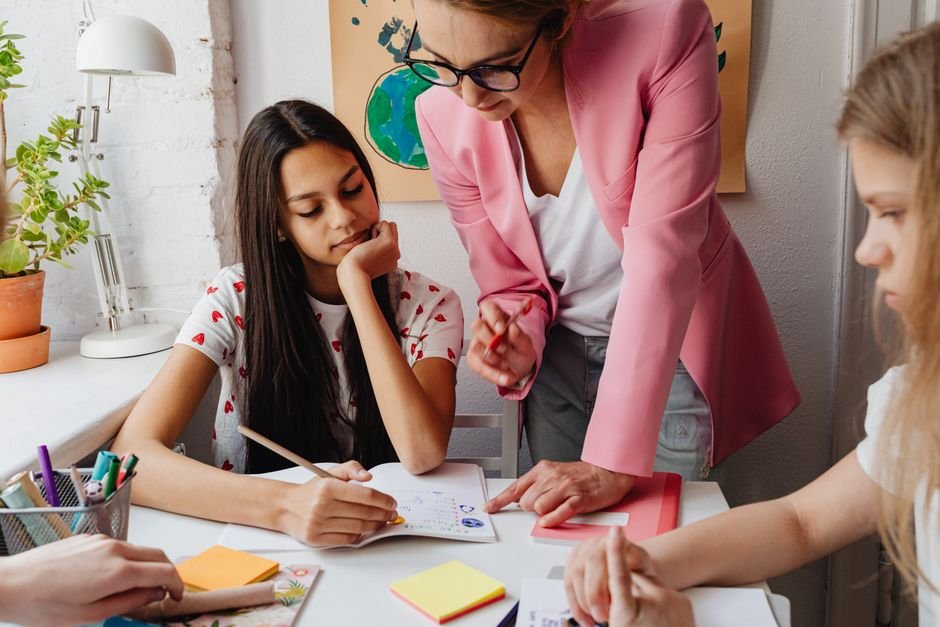 Teacher guiding ESL students through assigned roles on a classroom project