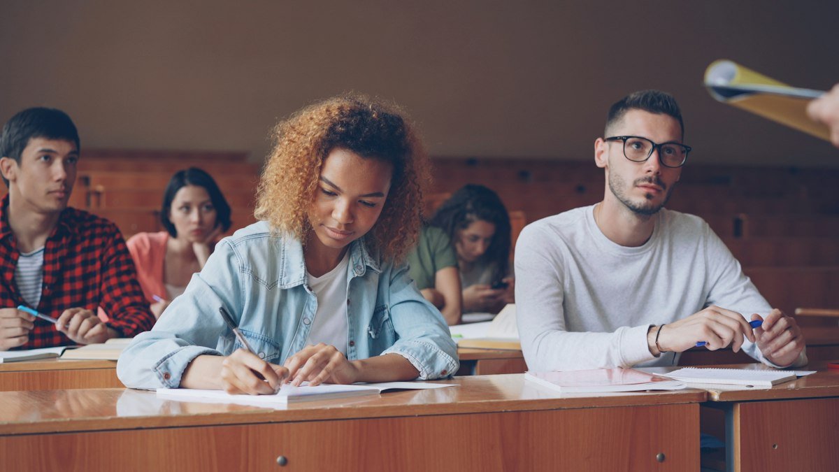 A student talking with an instructor in a lecture hall, illustrating how to practice school and learning idioms