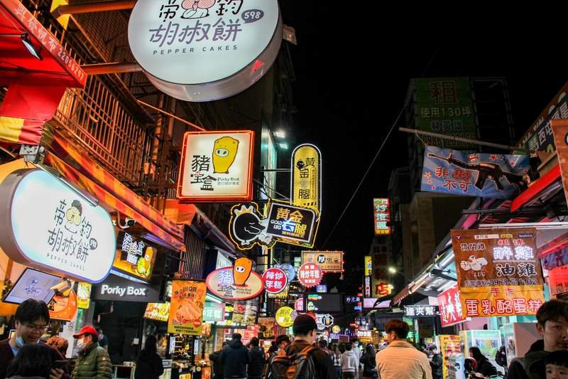 A Taiwan city street at night lined with buxiban cram school storefronts